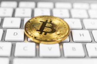 Bitcoin coin lying on white computer keyboard