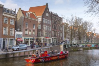 Amsterdam, Netherlands, March 31, 2016: Cruise boat at Amsterdam canals in Holland, bridge, people