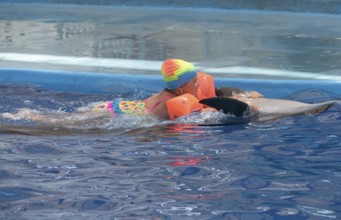 Little girl swim on dolphin in the pool