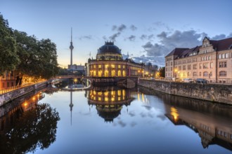 The Bode Museum and the television tower are reflected in the Spree in Berlin in front of sunrise