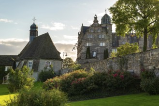 Historic Hämelschenburg Castle with castle church, well-tended garden and old walls in the evening