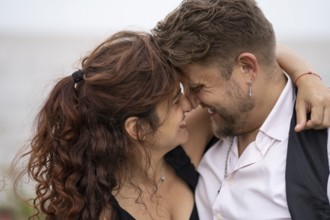 Couple looking into each other's eyes smiling about to kiss on a beach