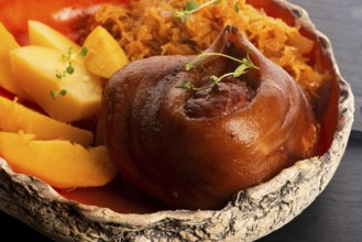 Appetizing baked pork knuckle with potatoes and cabbage on plate