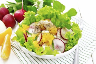Radish, onion and orange salad with mint, vegetable oil and spices on lettuce in a plate on a