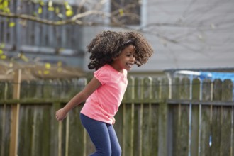 Kid toddler girl jumping on a playground in the backyard latin ethnicity