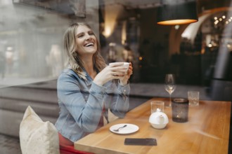 Blonde, attractive woman, 40+, sitting in a coffee house by the window