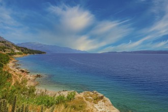 Coastal landscape with blue sea and green shore, peaceful sky with cloud patches, Makarska coast