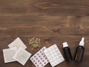 Tablets, drops and herbals on a dark wooden background with copy space. Flat lay or top view