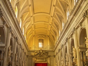 Brightly lit nave of a baroque church, decorated with high ceilings and long rows of columns,