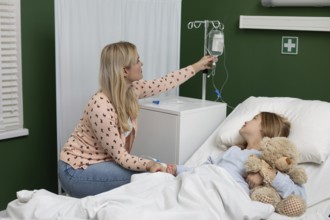In a hospital, a caring mother supports her child with an IV, who holds a beloved teddy bear for