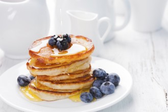 Pancakes with blueberry and honey on a white plate