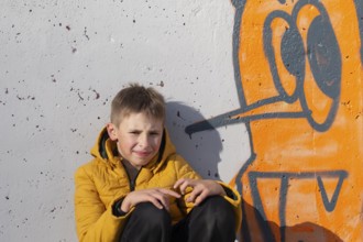 Boy teenager near the wall with funny graffiti