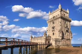 Belem tower and wooden bridge to it, Lisbon, Portugal at blue summer day sky with clouds. Medieval
