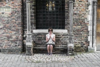 Playful portrait of a praying young tourist girl in Bruges, Belgium, July 2017, Europe