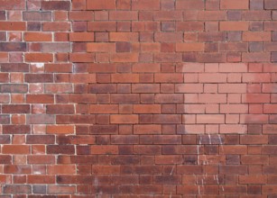 An old repaired patched exterior wall made of red bricks