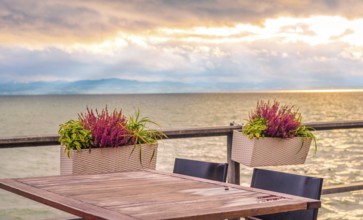 Conceptual image with an empty table, on a terrace, on the shore of the Bodensee lake, at sunset
