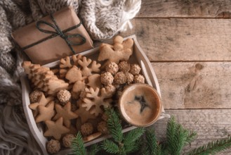 Cozy Christmas with a tray full of gingerbread, cookies and a cup of coffee, a fir twig, a gift,