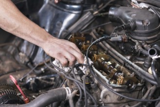 Auto mechanic working on car engine at repair service. Close up view