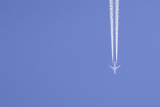 Airbus aircraft of Qatar airways flying across a blue sky with a vapour trail or contrail behind,