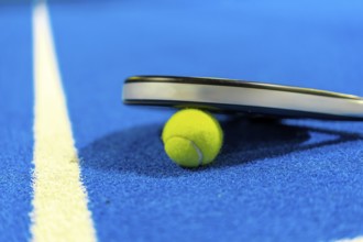 Close-up photo with copy space of paddle tennis racket on a ball