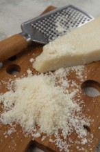 Freshly sliced and grated cheese, parmesan cheese, Gran gusto. Grana padano. on a wooden chopping