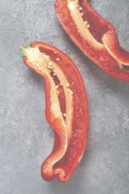 Fresh red peppers are sliced to reveal their bright interior, showcasing seeds and texture. The