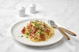 A delicious plate of spaghetti carbonara topped with crispy bacon, grated cheese, and fresh herbs