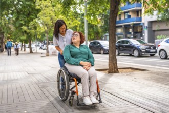 Asian woman pushing the wheelchair of a friend with disability along the city