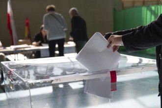 Voter's hand putting the vote into the ballot box.