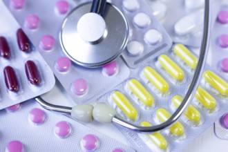 Blister packs with colorful pills alongside a stethoscope