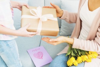 Daughter presenting gift box mom mother s day celebration