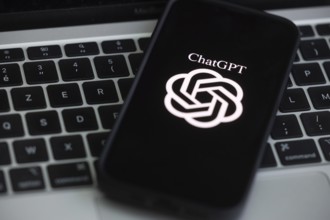 OpenAI software ChatGPT application on a mobile phone above a computer keyboard