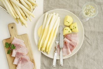 Traditional German dish with white asparagus, boiled ham, hollandaise sauce and potatoes, served on