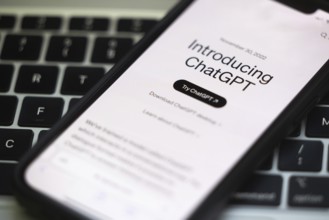 OpenAI software ChatGPT application on a mobile phone above a computer keyboard
