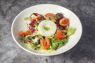 Green vegan salad from green leaves mix and vegetables. Top view on gray stone table