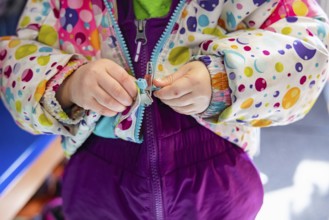 Close up shot on the hands of a kindergarten child struggling to latch and close the zipper of his