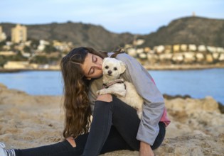 Girl playing with maltichon puppy dog in the beach