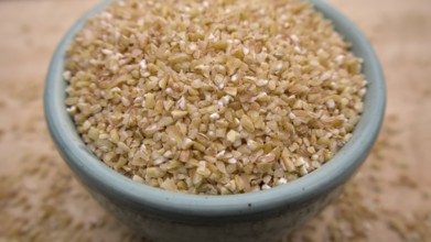 Broken Crushed Wheat (Dalia) in a Blue Bowl Isolated on Wooden Background, Close up