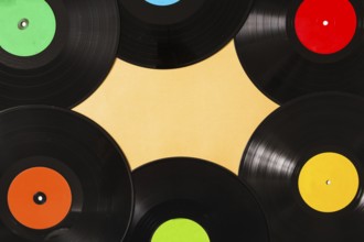 Overhead view colorful black vinyl record beige background