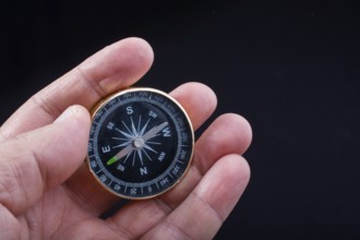 Child hand holding a compass on a black background