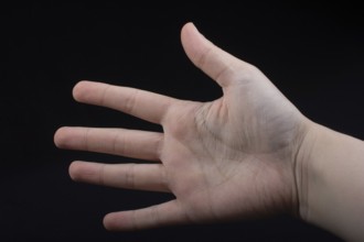Five fingers of a child hand partly seen in black background