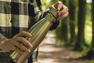 Close-up of Unrecognizable female hand holding Water bottle. Reusable steel thermo water bottle in