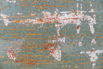 Peeling green, red, white and light brown paint on wooden board
