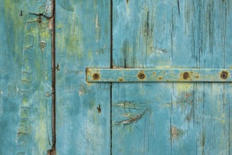 Old wooden door with peeling paint and iron fittings, texture, background, Montenegro, Balkans,