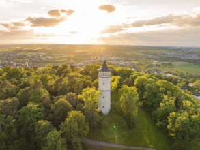 A tower rises in the sunset above the green forest and the vast countryside, Engelberg Tower,