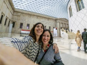 Two joyful female tourists capturing a selfie while enjoying their time in the stunning great court