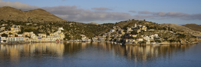Panoramic view of a harbour town with reflecting buildings in the calm water. Mediterranean scenery