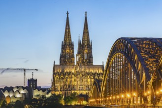 Cologne Cathedral, illuminated in the evening. Hohenzollern Bridge, railway bridge over the Rhine.