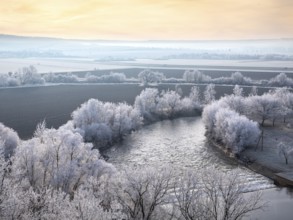 View of the river Unstrut in the Unstrut valley in winter at dawn, fields and trees covered with