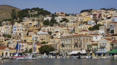 Colourful village stretches over hills with boats on the water and exudes Mediterranean serenity,